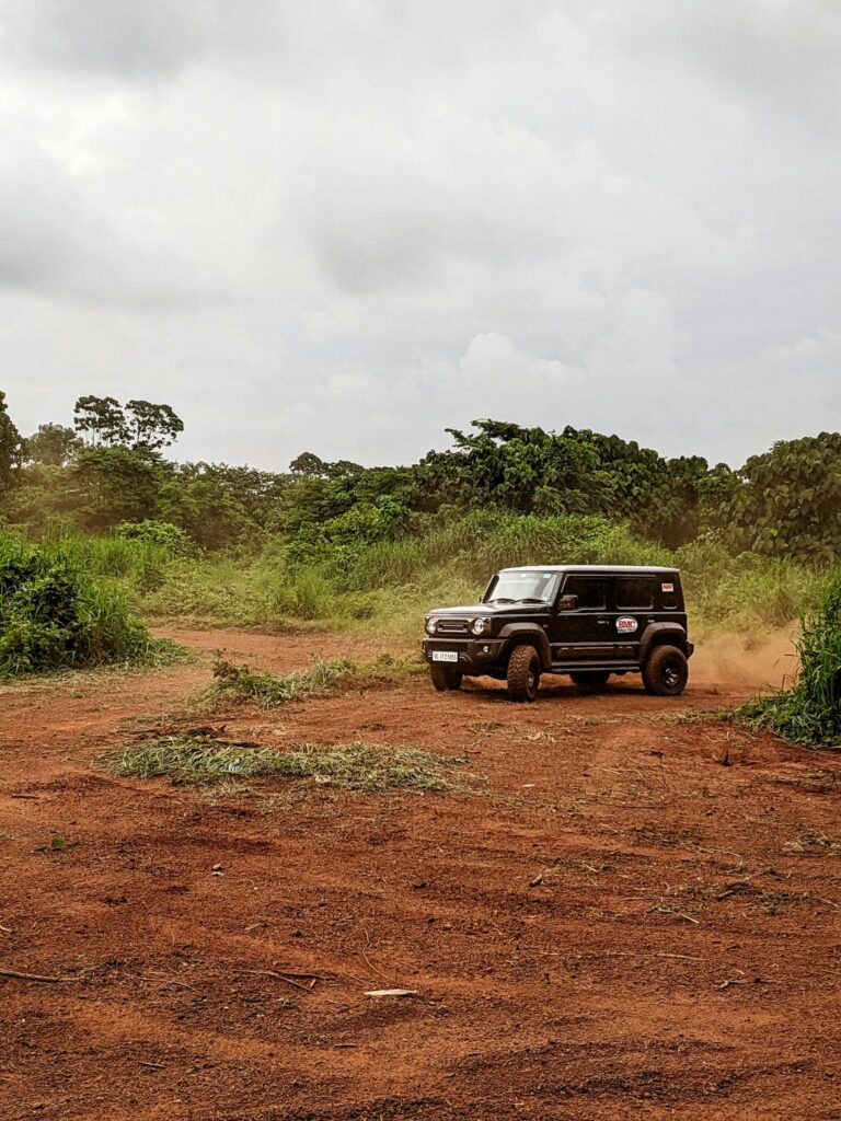 A black 4x4 vehicle navigating a muddy terrain during an off-road adventure under cloudy skies.